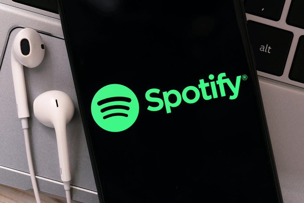 [Global] Higher than expected payroll taxes help Spotify swing into profit - phone screen with Spotify open beside earbuds, Spotify shares, Spotify makes a profit, Spotify subscriber numbers